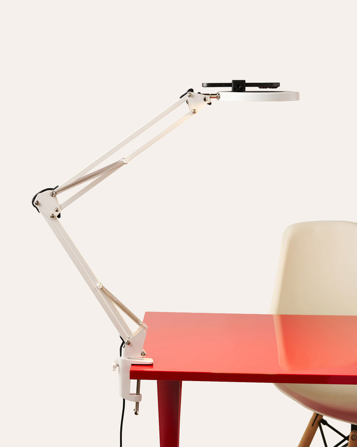 White adjustable Canvas LED desk lamp with LED light turned on.